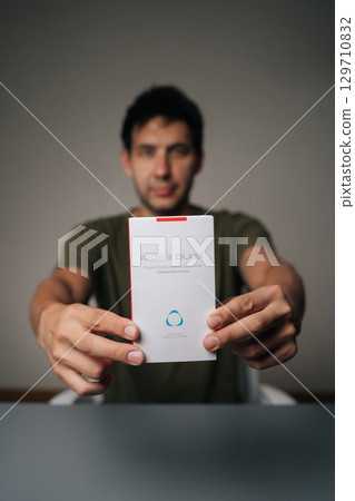 Ufa, Russia - 21 July 2025. Vertical portrait of blogger male holding and presenting new IQOC 3 duos tobacco heating system, innovative electronic cigarette for modern smokers seeking harm reduction Ufa, Russia - 21 July 2025. Vertical portrait of blogger male holding and presenting new IQOC 3 duos tobacco heating system, innovative electronic cigarette for modern smokers seeking harm reduction 129710832