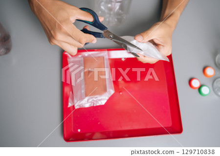 Top view of unrecognizable man cutting fertilizer bag, preparing nutrients for vertical hydroponic tower garden, embodying innovative urban agriculture techniques. Concept of home gardening. Top view of unrecognizable man cutting fertilizer bag, preparing nutrients for vertical hydroponic tower garden, embodying innovative urban agriculture techniques. Concept of home gardening. 129710838