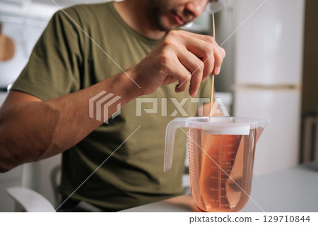 Close-up cropped shot of unrecognizable chemist in protective eyewear mixing chemical solution with stirrer inside sterile laboratory workspace, highlighting scientific research precision. Close-up cropped shot of unrecognizable chemist in protective eyewear mixing chemical solution with stirrer inside sterile laboratory workspace, highlighting scientific research precision. 129710844