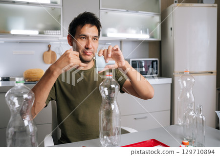 Gardener pouring organic fertilizer through funnel into plastic bottle, mixing nutrient-rich solution for healthy garden plants. Concept of healthy and sustainable cultivation. 129710894