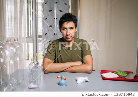 Portrait of confident biologist sitting at table, crossing arms while mixing fertilizer from recycled bottles for innovative vertical garden setup, emphasizing eco-friendly urban agriculture 129710948