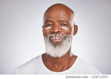 Facial cream, beauty and skincare of senior man in studio for self care with dermatology and cosmetics product on skin. Portrait of happy black male with sunscreen or lotion for glow and moisturizer Facial cream, beauty and skincare of senior man in studio for self care with dermatology and cosmetics product on skin. Portrait of happy black male with sunscreen or lotion for glow and moisturizer 129711057