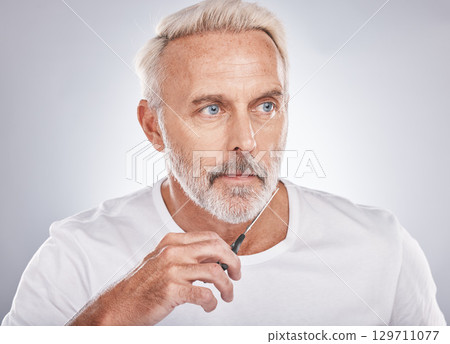 Scissors, wellness and man cutting beard on face for morning routine, grooming and cosmetic hygiene on a studio background. Barber, skincare and senior model trimming facial hair for clean beauty 129711077