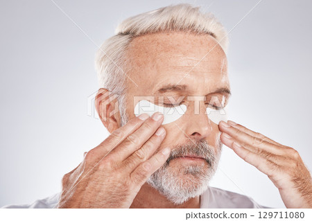 Eyes patch, senior man and skincare face in studio for self care dermatology, facial and cosmetics advertising in morning. Model with hands application of collagen mask or anti aging beauty product Eyes patch, senior man and skincare face in studio for self care dermatology, facial and cosmetics advertising in morning. Model with hands application of collagen mask or anti aging beauty product 129711080