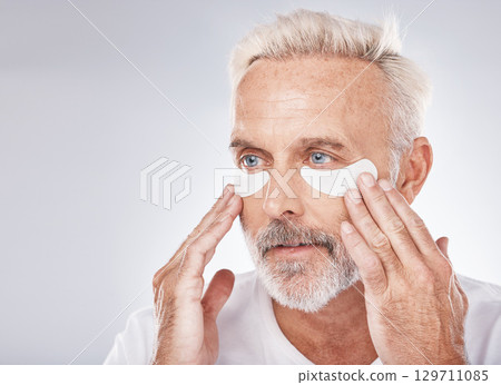 Skincare, eyes patch and man in studio for dermatology facial, face cosmetics or collagen mask advertising or marketing mockup. Senior model, hands application and eye patches or anti aging product Skincare, eyes patch and man in studio for dermatology facial, face cosmetics or collagen mask advertising or marketing mockup. Senior model, hands application and eye patches or anti aging product 129711085