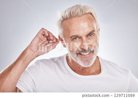 Senior man, cotton bud and ear cleaning or happy portrait in white studio background for grooming hygiene, wellness and wax removal. Elderly model, cosmetics ears cleaner and body care happiness 129711089