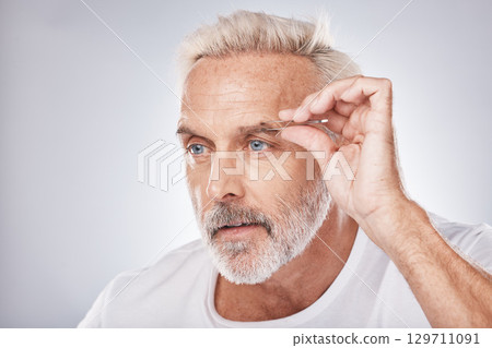 Man face, hand or tweezing eyebrow in grooming on gray studio background, facial self care or wellness beauty aesthetic. Headshot, mature model or hair removal tweezers in cleaning growth maintenance 129711091