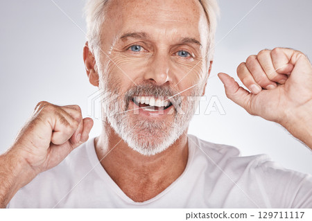 Face, dental floss and senior man in studio isolated on a gray background. Portrait, cleaning and elderly male model with product flossing teeth for oral wellness, tooth care and healthy gum hygiene 129711117