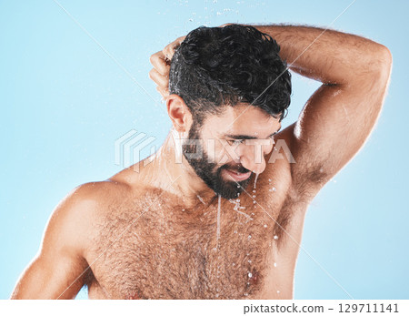Water, shower and a man washing hair with shampoo in studio on a blue background for beauty or hygiene. Hair, cleaning or treatment with a handsome male wet in the bathroom while bathing for haircare 129711141