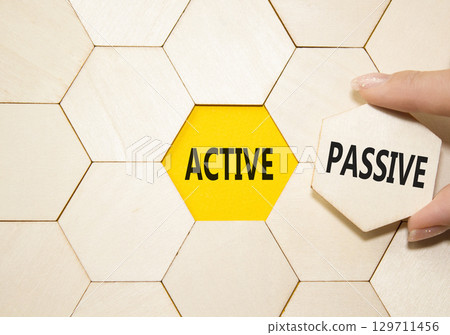 Active or Passive symbol. Concept word Active or Passive on wooden comb puzzle. Businessman hand. Beautiful yellow background. Business and Active or Passive concept. Copy space Active or Passive symbol. Concept word Active or Passive on wooden comb puzzle. Businessman hand. Beautiful yellow background. Business and Active or Passive concept. Copy space 129711456