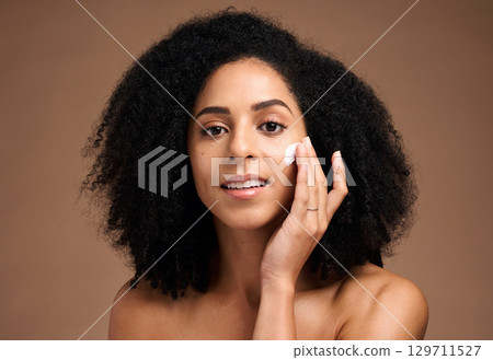 Face, cream and black woman in studio for skincare, beauty and cosmetics promotion with product application in portrait. African model with skin care, dermatology and sunscreen wellness in a headshot 129711527