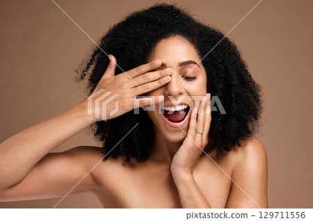 Happy black woman, hair and face with surprise and fun, hands with manicure, healthy skin and glow. Natural curly hair, hair care and cosmetic care with facial skincare against studio background 129711556
