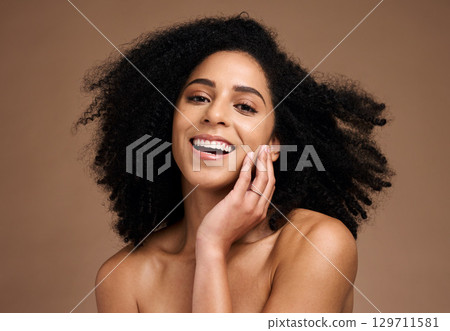 Woman, studio portrait and afro with beauty, makeup and cosmetic wellness with hands, face or natural hair. Model, skincare and facial cosmetics, self care glow and smile by brown studio background 129711581