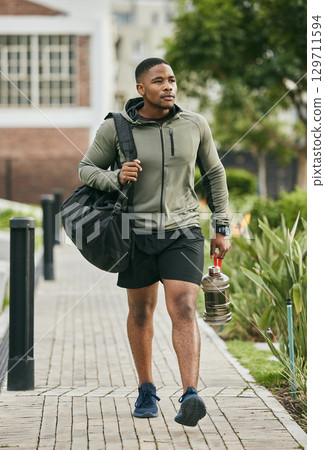 Fitness, travel or black man walking to gym for body training, exercise or workout with water bottle or gym bag in Atlanta. Path, mindset or healthy sports athlete with wellness goals or motivation 129711594