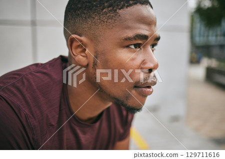 Face, fitness and exercise with a black man runner breathing alone outdoor in the city for cardio or endurance. Vision, motivation and workout with a male athlete training in an urban town for health 129711616