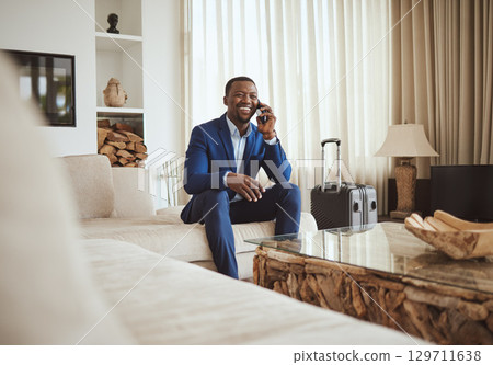 Happy businessman in hotel, on smartphone call and business communication for work in Atlanta. Young black entrepreneur, listening to audio on cellphone and sitting on luxury sofa in living room 129711638