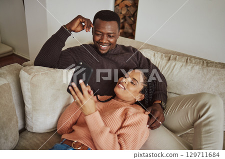 Black couple, phone and lounge couch while using home wifi for streaming internet or communication. Young man and woman talking while at home for social media app, online shopping and to relax Black couple, phone and lounge couch while using home wifi for streaming internet or communication. Young man and woman talking while at home for social media app, online shopping and to relax 129711684