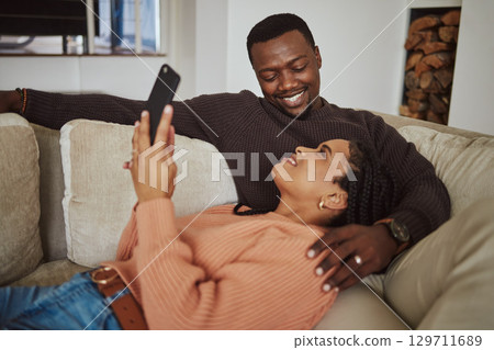 Black couple, phone and home wifi for internet connection while together on living room couch with love. Young man and woman talking while streaming online for communication or ecommerce subscription 129711689