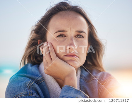 Sad, thinking and depression with woman at beach feeling stress, exhausted and problems. Mental health, crisis and anxiety with face of girl alone with frustrated, worry and confused by the sea 129711817