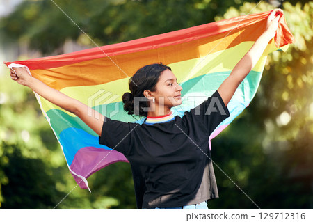 Rainbow, flag and human rights with an indian woman in celebration of lgbt gay pride alone outdoor. Freedom, equality and lgbtq with a happy female outside celebrating her equality or inclusion 129712316