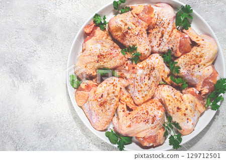 Marinated chicken wings prepared for grilling with spices and fresh herbs ready for cooking 129712501