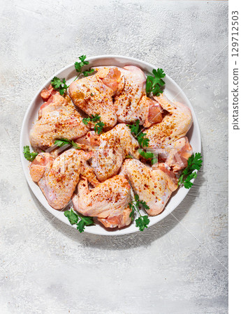 Marinated chicken wings prepared for grilling with spices and fresh herbs ready for cooking Marinated chicken wings prepared for grilling with spices and fresh herbs ready for cooking 129712503