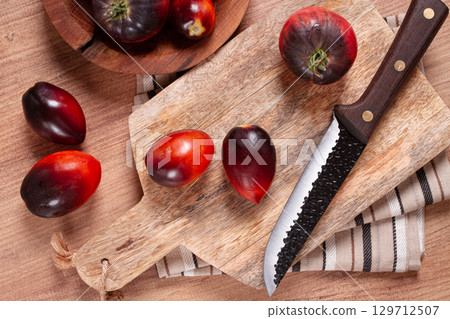 sliced tomatoes, Black Beauty variety, on a cutting board, top view,on the kitchen table, 129712507
