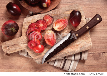 sliced tomatoes, Black Beauty variety, on a cutting board, top view,on the kitchen table, 129712508