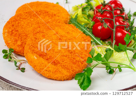 crispy fried fish cutlets, fish burgers, on a white plate, with fresh lettuce leaves, arugula and cherry tomatoes, homemade, no people, 129712527