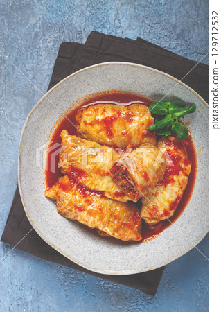 Stuffed cabbage rolls with minced meat, in tomato sauce, top view, without people, in the spotlight. 129712532