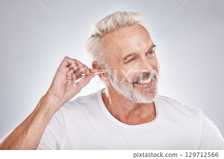 Elderly man, ear cleaning with cotton swab for hygiene, grooming and clean body with cosmetic care against studio background. Beauty, health and wellness, senior male and happy with natural cosmetics 129712566