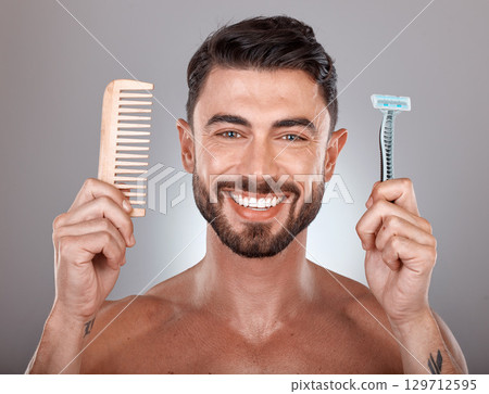 Portrait, shaving and comb with a man model holding a razor in studio on a gray background for skincare. Face, wellness and hands with a handsome young male in the bathroom to shave his beard 129712595