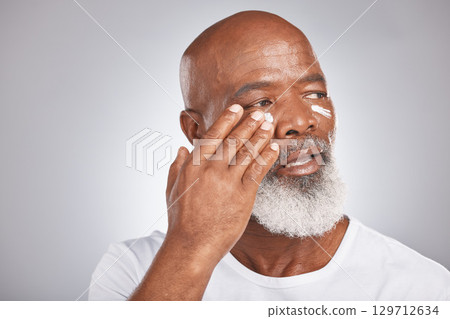 Skincare, beauty or old man with facial cream marketing or advertising luxury beauty product for self care. Studio background, mockup space or senior black mans hand applying facial mask or cosmetics Skincare, beauty or old man with facial cream marketing or advertising luxury beauty product for self care. Studio background, mockup space or senior black mans hand applying facial mask or cosmetics 129712634