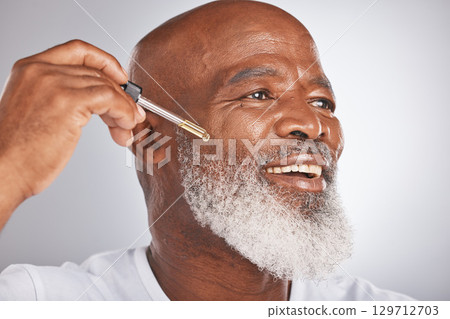 Skincare, wellness and man with a face serum in a studio for a healthy, cosmetic and natural routine. Beauty, cosmetics and African male with a facial oil treatment isolated by a gray background. 129712703