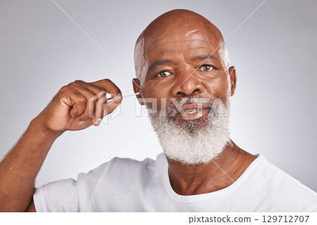 Senior black man, ears cleaning and cotton bud for wax removal, grooming hygiene and self care cosmetics earwax cleaner in white studio background. Elderly african model, face and body care cleansing Senior black man, ears cleaning and cotton bud for wax removal, grooming hygiene and self care cosmetics earwax cleaner in white studio background. Elderly african model, face and body care cleansing 129712707