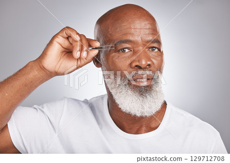 Senior black man, eyebrow and tweezer for self care and grooming for clean, glow and fresh skin and face. Portrait of African male for facial hair removal or epilation on grey studio background 129712708