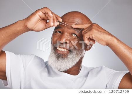 Black man, eyebrow hair and tweezer for self care, hair removal and epilation for beauty and grooming. Headshot of happy senior male on grey studio background for body care, hygiene and clean skin 129712709
