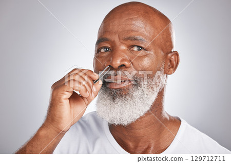 Senior man, nose hair and tweezer for self care, hair removal and epilation for beauty and grooming . Headshot of black male with beard on grey studio background for body care, hygiene and clean skin 129712711