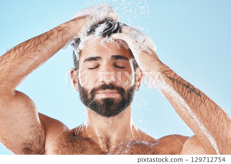 Hair care, face water splash and shower of man in studio isolated on a blue background. Water drops, shampoo and male model washing, cleaning or bathing for healthy skin, wellness or skincare hygiene Hair care, face water splash and shower of man in studio isolated on a blue background. Water drops, shampoo and male model washing, cleaning or bathing for healthy skin, wellness or skincare hygiene 129712754
