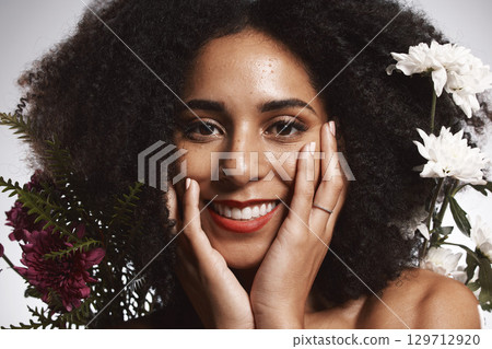 Portrait, beauty and flowers with a model black woman in studio on a gray background touching her face. Skincare, plant and cosmetics with an attractive young female posing to promote natural care 129712920
