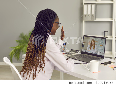 Two young business women greeting each other at online work meeting via video call 129713032