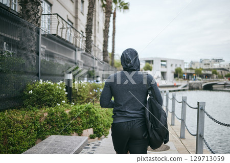 Fitness, hoodie or man walking to gym for body training, exercise or workout with a duffle bag in Miami, Florida. City, mindset or healthy sports athlete with wellness goals, motivation or mission 129713059