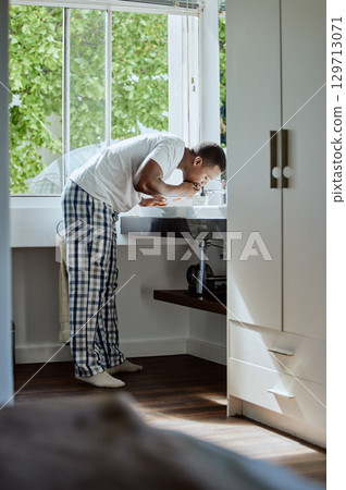 Black man brushing his teeth for dental health, hygiene or wellness in the bathroom of his home. Grooming, healthcare and young African guy cleaning his mouth for an oral care morning routine. 129713071
