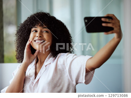 Selfie, beauty and skincare with a black woman taking a picture in the bathroom of her home in the morning. Facial, phone and influencer with an attractive female posing for a social media photograph 129713086