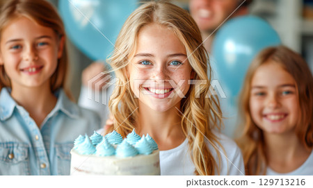 Young girl smiling with birthday cake and friends celebrating with balloons in a joyful atmosphere 129713216