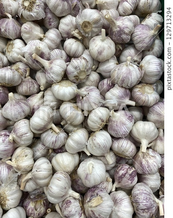 Garlic bulbs piled in abundance as a background showcasing fresh produce and healthy eating Garlic bulbs piled in abundance as a background showcasing fresh produce and healthy eating 129713294