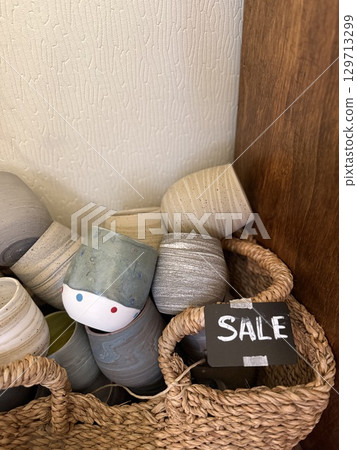 Ceramic cups in basket with sale sign in cozy home decor shop display 129713299