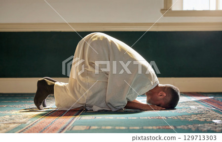 Islam, religion and prayer of a muslim man at mosque in ramadan for spiritual faith, God and belief while doing religious worship. Islamic or Arab culture people sitting to pray at holy place 129713303
