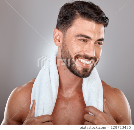 Man with towel, beauty and face with skincare, hygiene and self care against studio background. Grooming, skin and glow with cosmetic, facial wellness and happy male with beard, clean teeth and smile 129713430