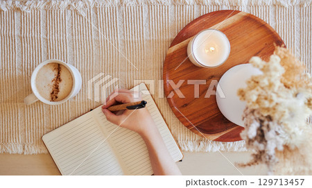 Coffee, hand and writing in journal top view with candle for calm, peace and relax morning routine. Woman, notebook and diary planning goals, lifestyle motivation or creative writer with warm drink Coffee, hand and writing in journal top view with candle for calm, peace and relax morning routine. Woman, notebook and diary planning goals, lifestyle motivation or creative writer with warm drink 129713457